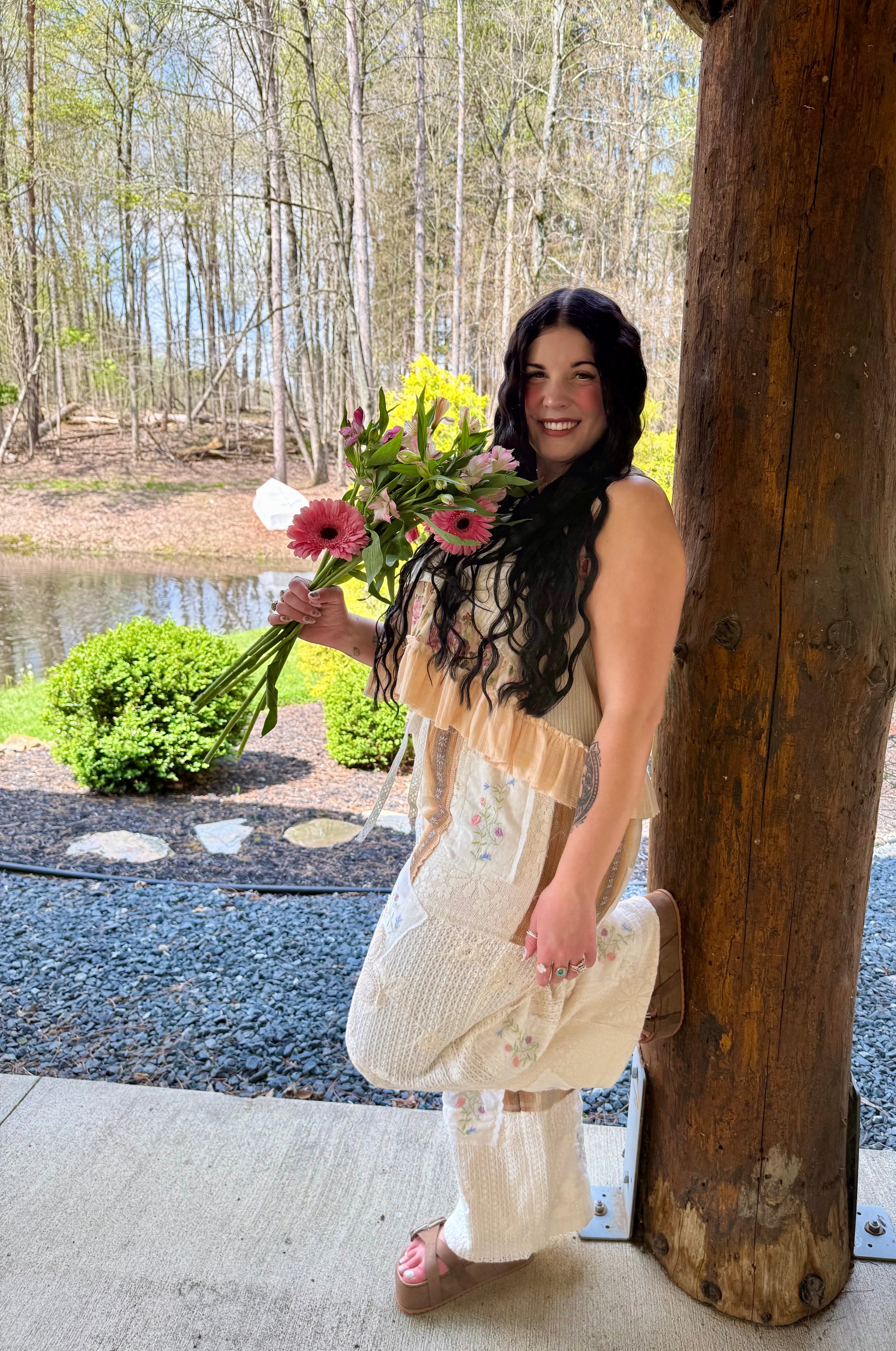 Woman holding flowers by a wooden structure with a natural background