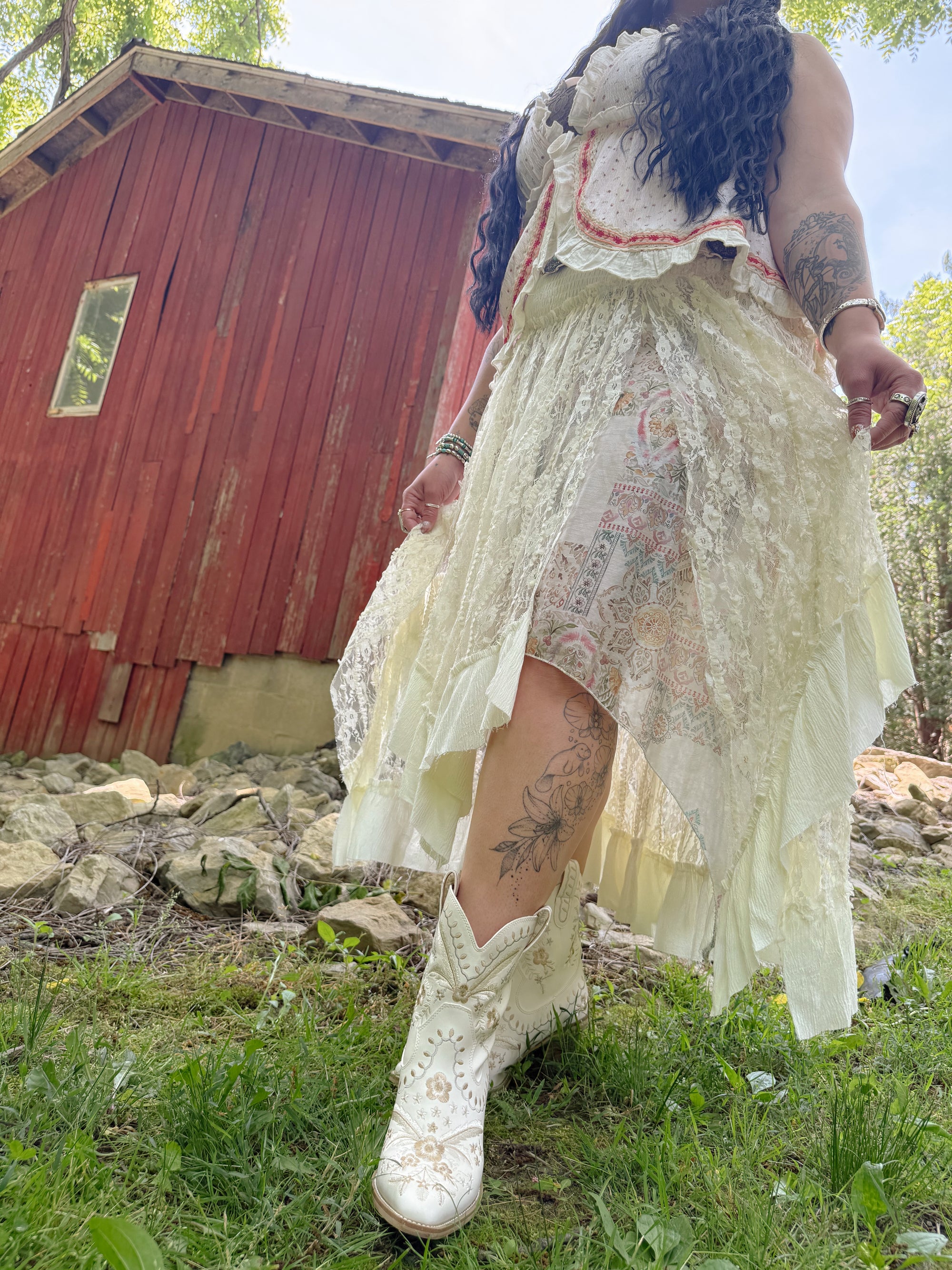 Person wearing a white lace dress standing outdoors with a red building in the background