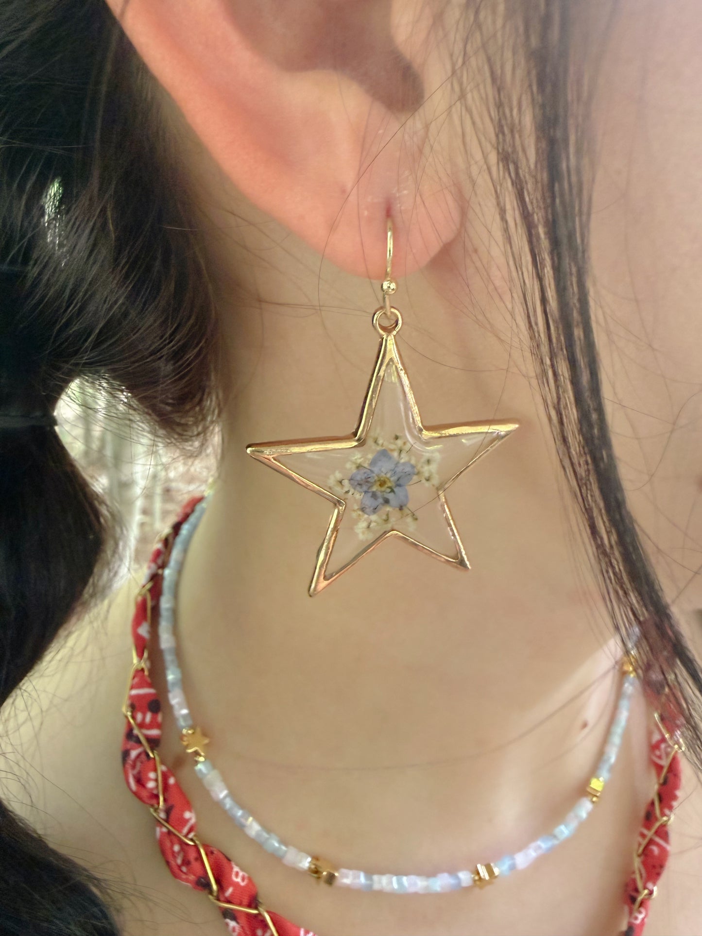 Star-shaped earring with floral design worn by a person