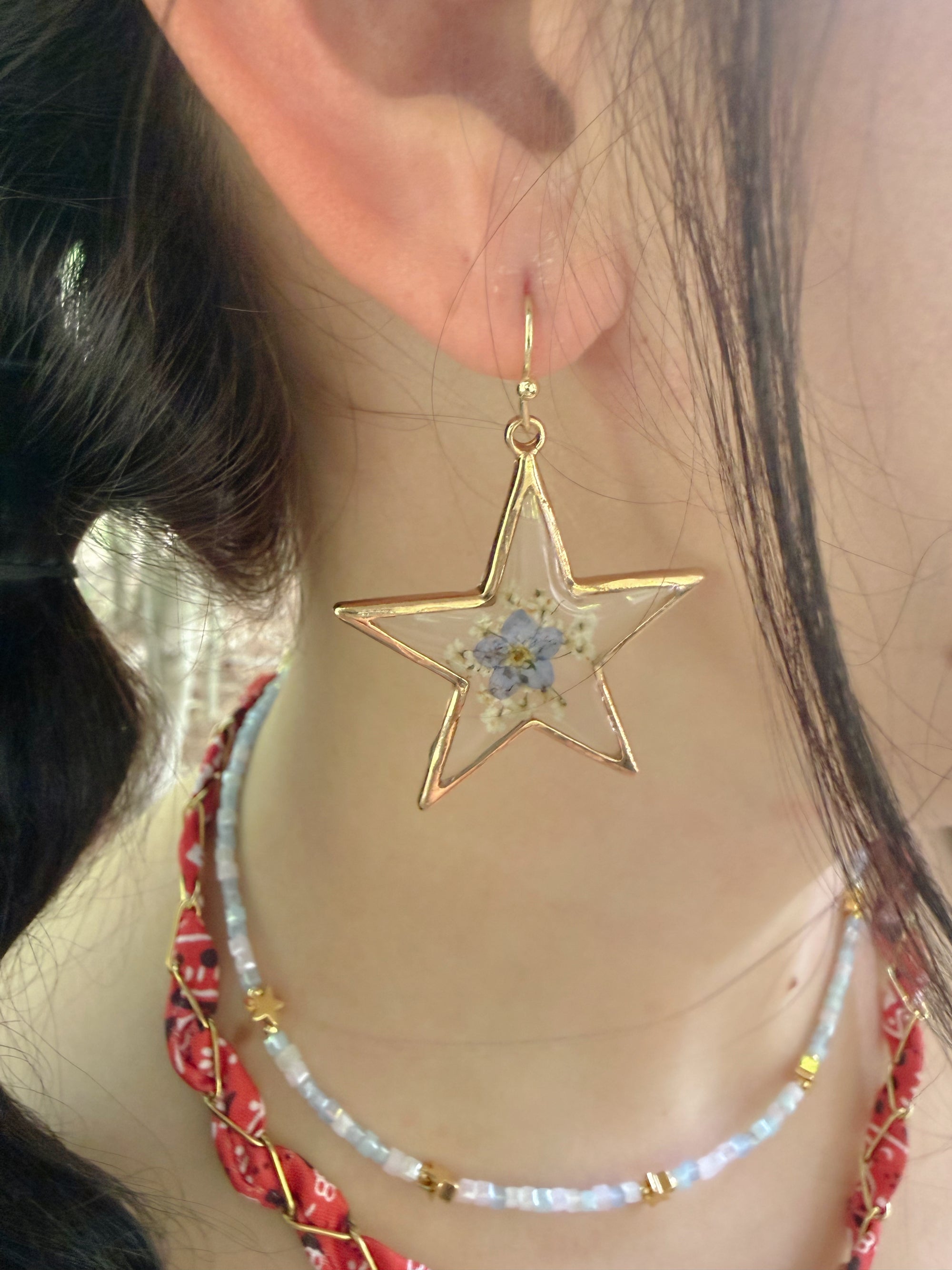 Star-shaped earring with floral design worn by a person