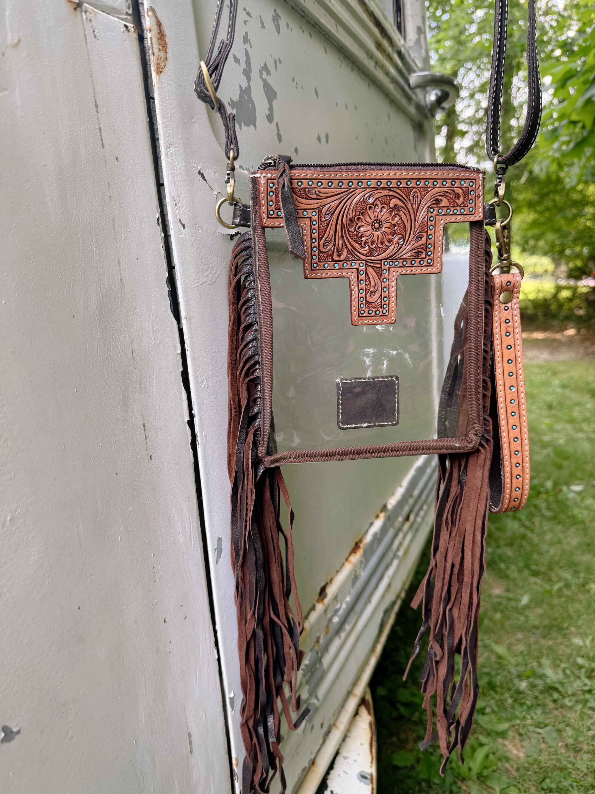 Brown leather crossbody bag with decorative patterns on a white surface